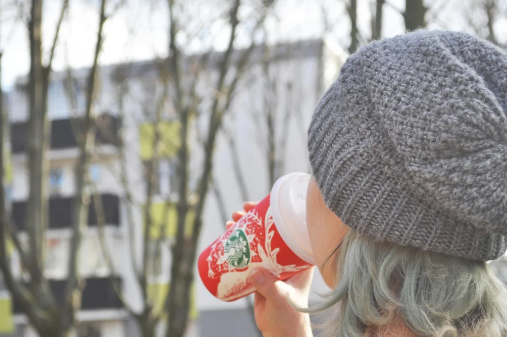 Woman drinking from a Red Starbucks Holiday Themed Cup. Photo by Kristi Gy.